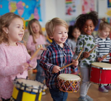 Kindergartenkinder spielen auf Trommeln