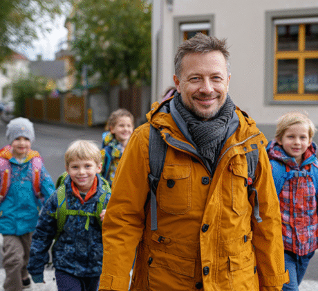 Erzieher ĂŒberquert einen Zebrastreifen mit Kindergartenkinder