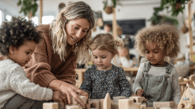 Spielbegleitung von Erziherin mit drei U3-Kindern mit Holzbauklötzen