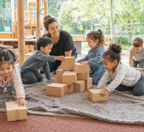 Erzieherin mit Kindern im Gruppenspiel mit vielen Kartons.