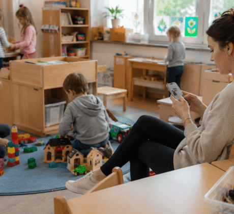 Erzieherin daddelt am Handy in Kita-Gruppenraum