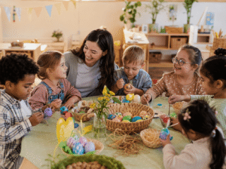 Kinder bemalen Ostereier in der Kita an einem runden Tisch
