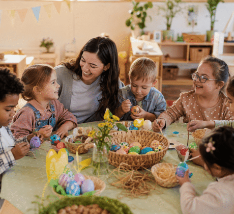 Kinder bemalen Ostereier in der Kita an einem runden Tisch