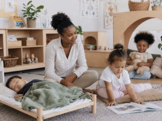 Erzieherin it drei Kindern in Gruppenraum in der Mittagszeit. Eins schläft, ein anderes liest und ein weiteres ist in der Kuschelecke